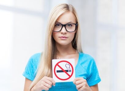 a girl holding a no smoking sign at the entrance